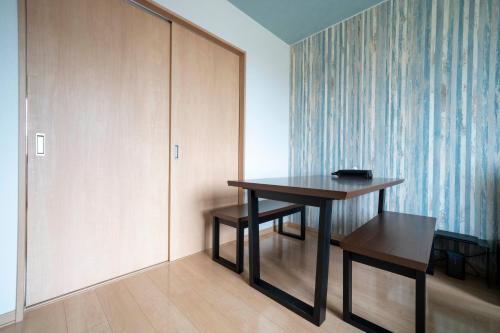 a room with a table and a bench and a wall at Lambent in Kami-furano