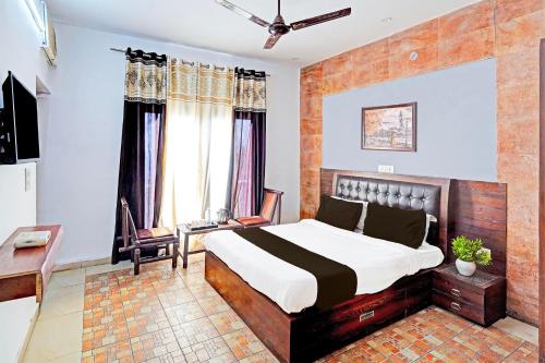 a bedroom with a bed and a desk and window at Hotel O 9 Palm in Rājpur