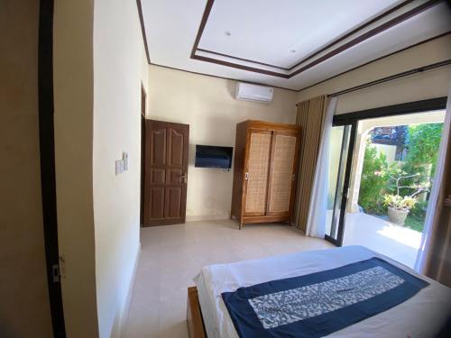 a bedroom with a bed and a sliding glass door at Oemah Dharma Garden View by EPS in Gianyar