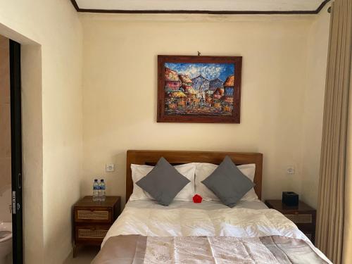 a bedroom with a bed and a painting on the wall at Oemah Dharma Garden View by EPS in Gianyar
