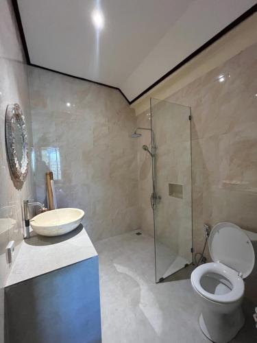a bathroom with a toilet and a glass shower at Oemah Dharma Garden View by EPS in Gianyar