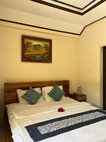 a bedroom with a white bed with a picture on the wall at Oemah Dharma Garden View by EPS in Gianyar
