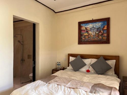 a bedroom with a bed and a painting on the wall at Oemah Dharma Garden View by EPS in Gianyar