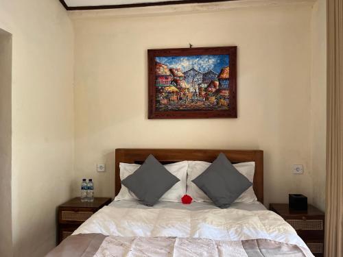 a bedroom with a bed with a painting on the wall at Oemah Dharma Garden View by EPS in Gianyar