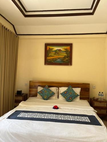 a bedroom with a white bed with pillows at Oemah Dharma Garden View by EPS in Gianyar