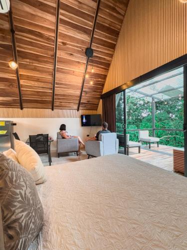 a bedroom with a bed and people sitting in chairs at River Paradise Cabin with Private Jacuzzi in Fortuna