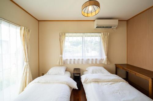 three beds in a room with a window at O-KiNAWA HOUSE in Onna