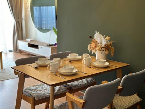 a wooden table with cups and saucers on it at Youth City Residences by Manhattan Group in Nilai