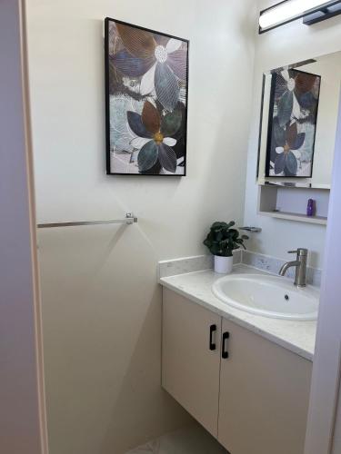 a white bathroom with a sink and a mirror at Drift & Discovery New Modern Stay, Mins to Beach! in Brissett Run