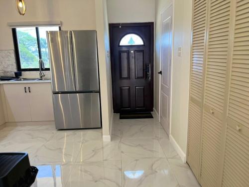 a kitchen with a stainless steel refrigerator and a door at Drift & Discovery New Modern Stay, Mins to Beach! in Brissett Run