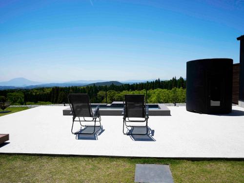 Dos sillas sentadas en un patio con vista. en FOG villa&spa, en Kirishima