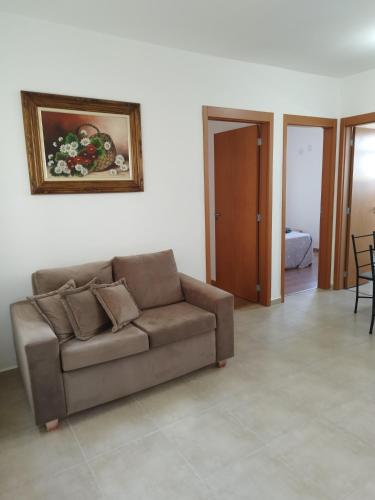 a living room with a couch and a painting on the wall at Apartamento novo e aconchegante! in Jaboticabal