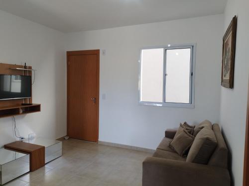 a living room with a couch and a television at Apartamento novo e aconchegante! in Jaboticabal