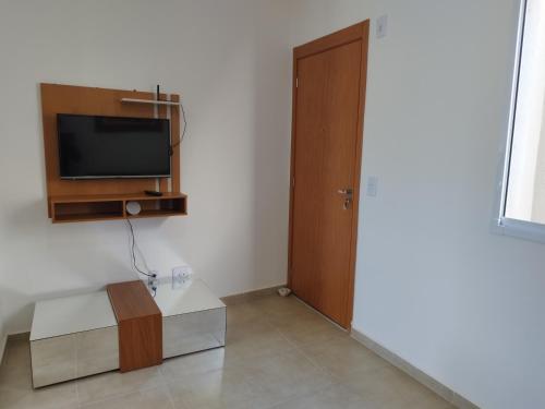a living room with a television and a door at Apartamento novo e aconchegante! in Jaboticabal