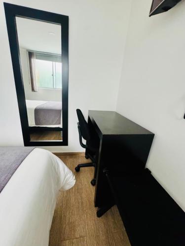 a bedroom with a desk and a mirror next to a bed at HOTEL JARDIN 38 in Pasto