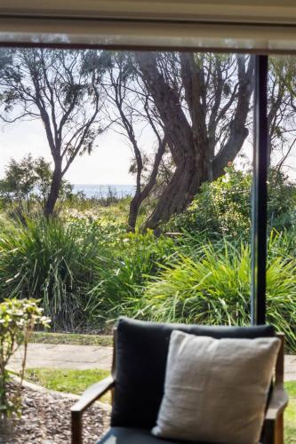 a couch with a pillow in front of a window at 2 CapeView Beachfront Geographe Bay in Broadwater