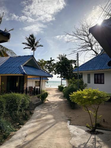 a house with a blue roof next to the ocean at Pranee Bungalow in Koh Tao