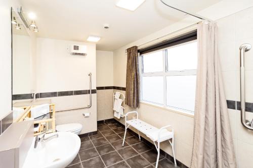 a bathroom with a sink toilet and a window at Balmoral Lodge Motel in Invercargill