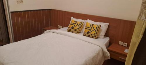 a bed with yellow and black pillows on it at Bintang Khanida Syari'ah in Tjakranegara