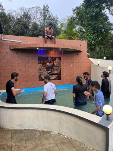 a group of people standing around a swimming pool at Greenspun Nature stay in Somvārpet