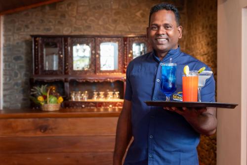 a man holding a tray of drinks in a bar at Mirage Kandyan Heights in Kandy