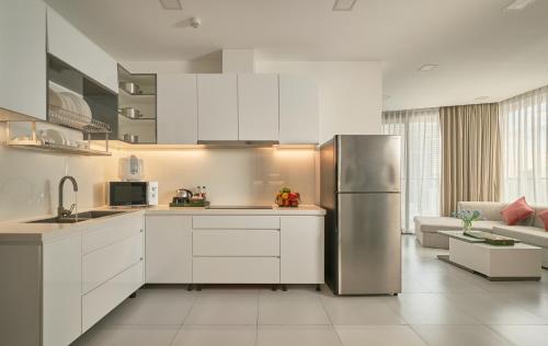 a kitchen with white cabinets and a stainless steel refrigerator at Noden Hotel & Apartment in Phnom Penh