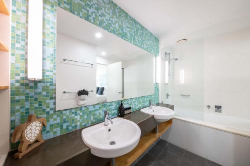 a bathroom with two sinks and a mirror at Marina Waterfront Living at Port of Airlie in Airlie Beach