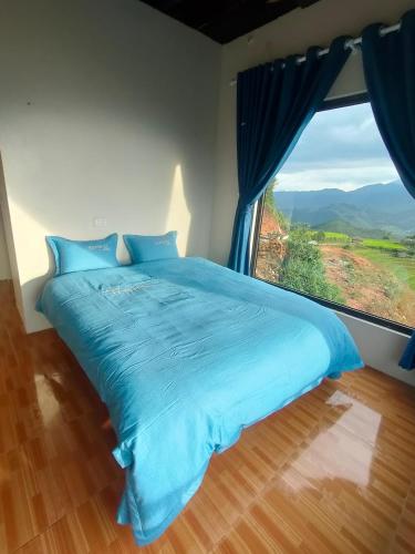 a blue bed in a room with a large window at Homestay Chù Chỏ in Mù Cang Chải