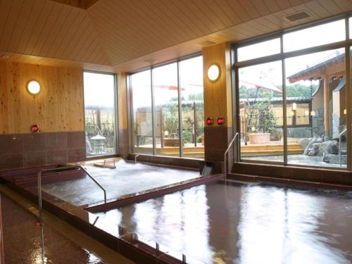 a large pool of water in a room with windows at Nanaironoyu Hotel in Takeo