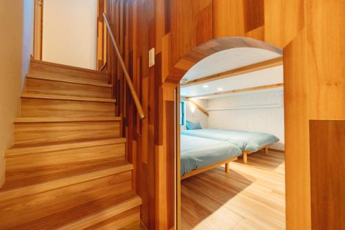 a bedroom with a bed in a room with wooden floors at YOUR ROOM treehouse KUMAMOTO in Kumamoto