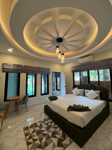 a bedroom with a large bed with a ceiling at VS Resortวีเอส รีสอร์ท ท่าศาลา in Ban Thang Khun