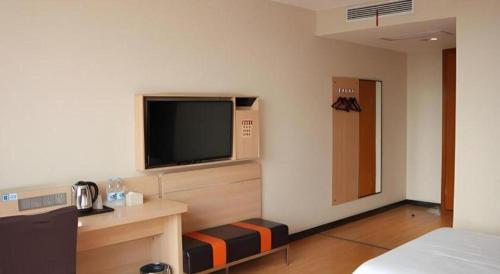 a hotel room with a television on the wall at 7Days Premium Yichang Railway Station East in Yichang