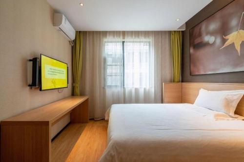 a bedroom with a large bed and a television at IU Hotel Kunming Jinma Bijifang Joy City in Kunming