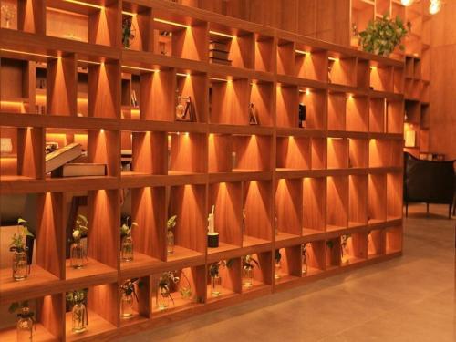 a wall of wooden shelves with plants on them at James Joyce Coffetel·Anyang Text Museum in Anyang