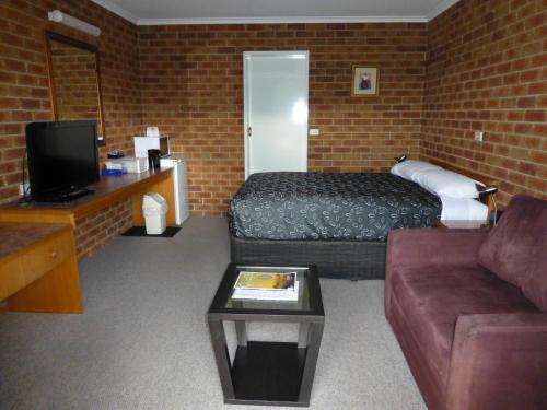 a hotel room with a bed and a couch at Inverloch Central Motor Inn in Inverloch