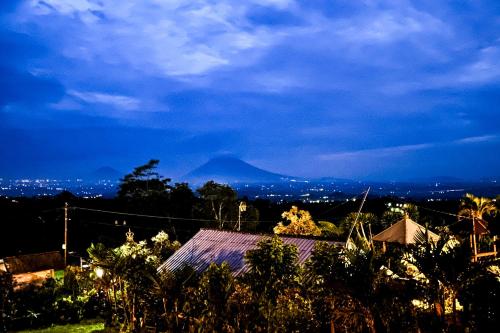 a view of a city at night with a mountain at Munduk Luwih Ecolodge Bedugul by AGATA in Tabanan
