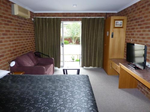una camera d'albergo con letto, divano e TV di Inverloch Central Motor Inn a Inverloch