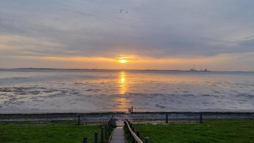 a sunset over the water with the sun setting at Ferienhaus Namenlos in Butjadingen
