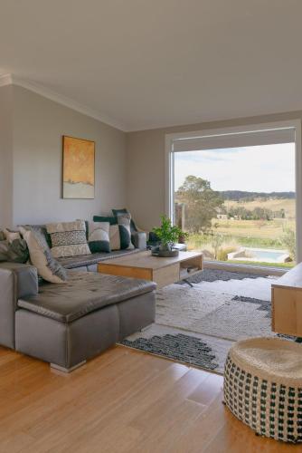 a living room with couches and a large window at Milton Woodstock Homestead Luxury retreat with NEW 11M POOL just minutes from the beach in Milton