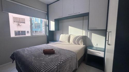 a small bedroom with a bed with a brown purse on it at Apê central BC | 450m da praia + A/C + vaga in Balneário Camboriú