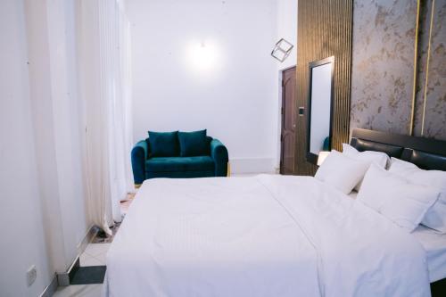 a bedroom with a white bed and a blue chair at Villa Di Angelo Negombo in Negombo