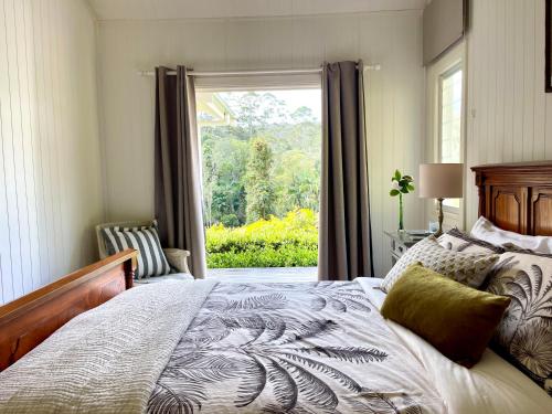 a bedroom with a bed and a large window at Nightcap Ridge - Byron Bay Hinterland in Dorroughby