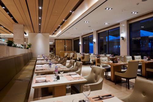 a restaurant with long tables and chairs and windows at Hotel Hyundai by Lahan Ulsan in Ulsan
