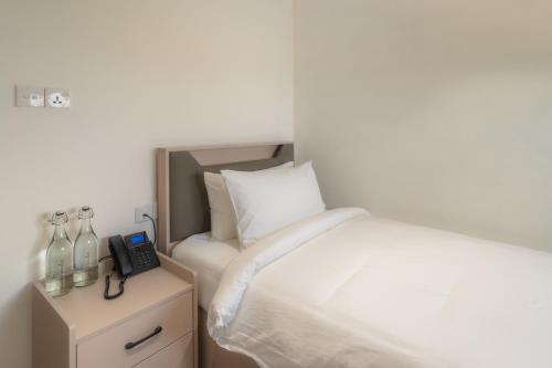 a bedroom with a white bed and a telephone at Nest by Hawks Hotels Kamadhoo Baa Atoll in Kamadhoo