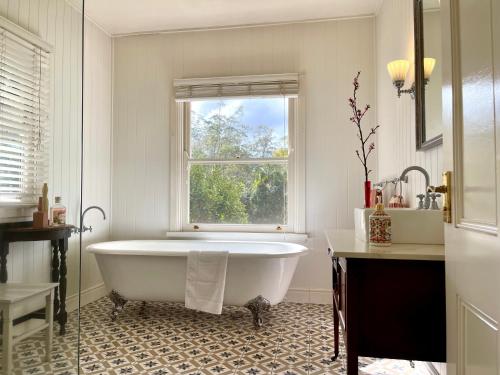a white bathroom with a tub and a window at Nightcap Ridge - Byron Bay Hinterland in Dorroughby