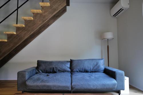 a blue couch in a living room with a staircase at 伊勢志摩パールヴィレッジ ヴィラ in Shima