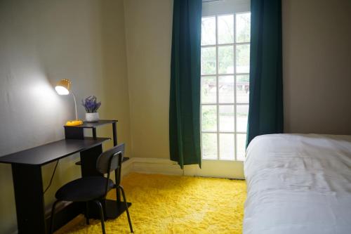 a bedroom with a bed and a desk and a window at Cute Neighborhood Rainbow Apt in Saint Louis