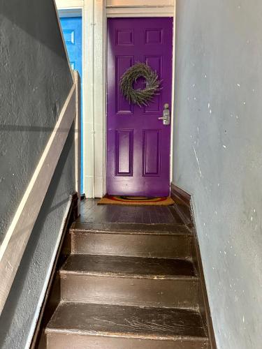 a purple door with a wreath on a stairs at Cute Neighborhood Rainbow Apt in Saint Louis