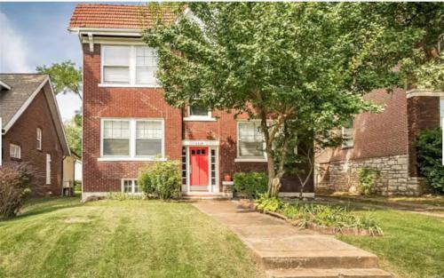 a brick house with a red door and a yard at Cute Neighborhood Rainbow Apt in Saint Louis