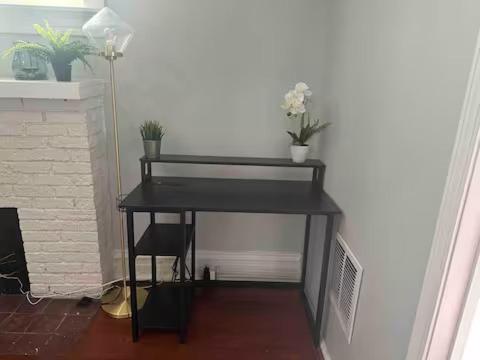 a black desk with flowers and a chair in a room at Cute Neighborhood Rainbow Apt in Saint Louis